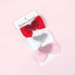 Close-up of three bow hair clips with glitter hearts on white display card