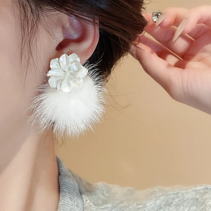 Gros plan sur des boucles d'oreilles fleurs blanches avec pompons doux pour femmes