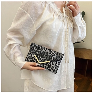 Detail of leopard print envelope bag with gold V-clasp and metallic chain strap
