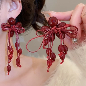 Detail of red beaded bow earrings with cascading tassels and retro resin accents