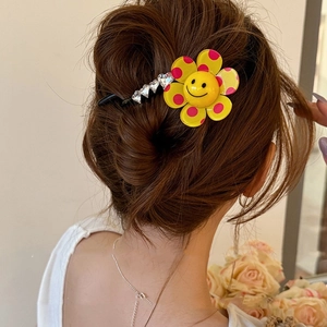 Detail of yellow flower hair clip with smiley face and crystals on a stylish updo