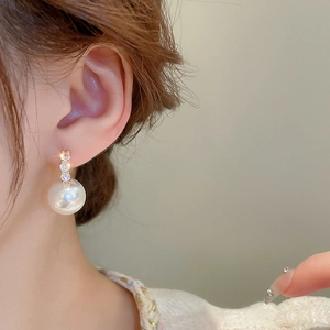 Close-up of elegant gold plated pearl drop earrings with sparkling zircon accents