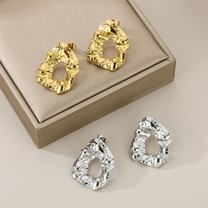 Macro shot of irregular hollow earrings with gold and silver hammered metal texture