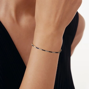Detail showing 2mm gold-plated tennis bracelet with blue and white stones on wrist