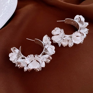 Vue détaillée de boucles d'oreilles fleuries argentées sur du tissu en soie