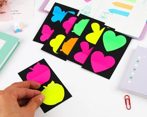 Macro shot of fluorescent colorful shaped PET index tabs being peeled from black backing