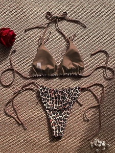 Flat lay of leopard print bikini set with brown halter top on woven straw mat background