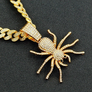 Macro shot of gold-plated spider pendant with dense rhinestones on Cuban link chain