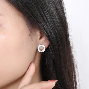 Close-up of a silver geometric hollow round stud earring with pavé-set crystals on a model