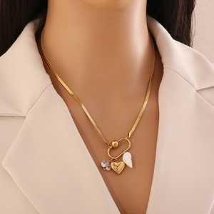 Gold snake chain necklace with shell and heart charms on a female model