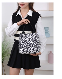 Fashionable large leopard print tote bag shown held by a model in a modern home setting