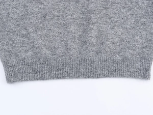 Détail du pull en tricot gris montrant la texture douce et l'ourlet côtelé