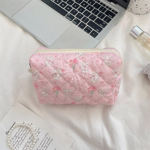 Detail view of pink quilted cosmetic bag with cute rabbit and flower print on a desk