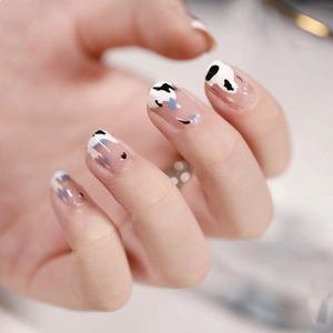 Cow pattern heart nail stickers with purple accents on hand with marble background
