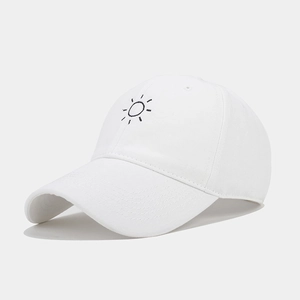Detail view of white cotton baseball cap with sun embroidery from a 45-degree angle
