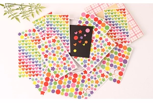 Flat lay of colorful heart star and round stickers with a pink plaid notebook decoration
