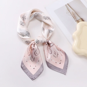 Detailed close-up of a pink paisley silk scarf with dark grey edges on white background