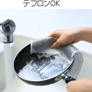Close-up of non-scratch wire dishcloth cleaning a black frying pan with soap foam