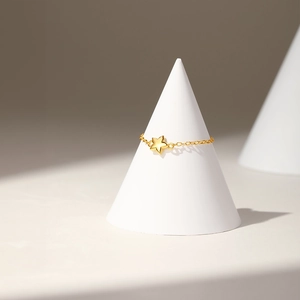 Detailed view of adjustable gold star chain ring on a minimalist white display stand