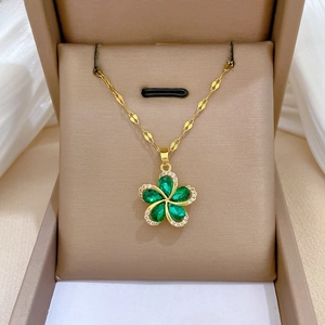 Detail of a rotating green crystal flower pendant on a gold titanium steel necklace