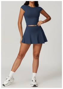 Detail view of navy blue high-waisted pleated tennis skirt and cropped tight sports top