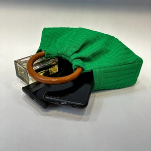 Detail of green pleated evening bag with round wooden handle and interior items