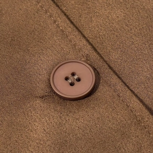 Detail of brown button and faux suede fabric texture on a long stylish trench coat