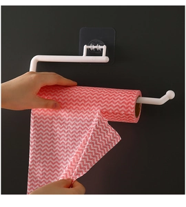 Close-up of wall-mounted white paper towel holder with adhesive strip on grey wall