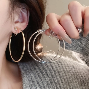 Macro view of oversized gold and silver hoops showing high-shine metal finish and quality