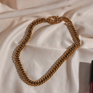 Close-up of golden chunky chain necklace with large OT toggle clasp on satin background