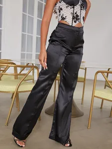 Detail of high-waisted black satin trousers and white lace bodice with metallic sheen