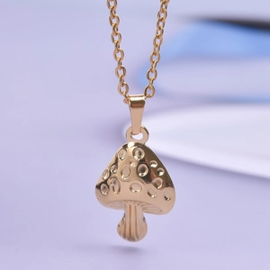Macro detail of golden mushroom pendant necklace featuring textured metallic surface