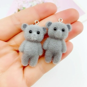 Close-up of grey flocked mini bear charms with silver metal rings held in a hand