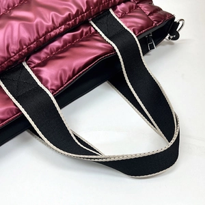 Close-up of wine red quilted fabric and woven shoulder strap on a metallic handbag