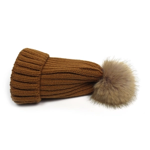 Detail of a brown ribbed knit hat featuring a large fluffy faux fur pom-pom on the top