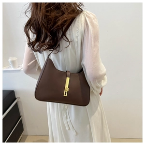 Detail of dark brown leather underarm bag with gold vertical metal buckle and shoulder strap