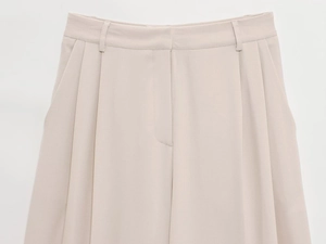 Détails du pantalon large crème montrant la structure de la taille et les plis marqués