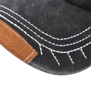 Detailed macro view of gray washed cotton cap brim with brown leather trim and white stitching