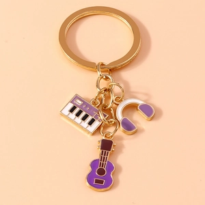 Detailed close-up of golden music keychain with purple enamel piano, guitar and headphone charms