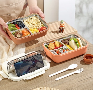 Three-compartment stainless steel bento box lid used as a mobile phone holder