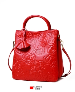 Vista laterale di una borsa in pelle rossa con goffratura di rose 3D e texture in pelle grana