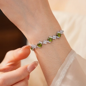 Close-up of silver zircon bracelet featuring oval green gemstone and floral details