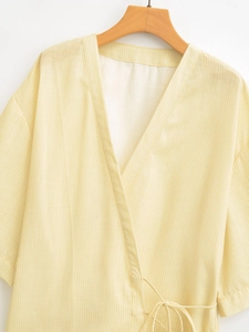 Detail of light yellow striped kimono top with V-neckline and delicate waist tie closure