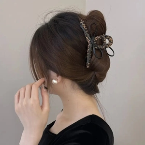 Elegant leopard print bow claw clip for women's bun hairstyle accessory shown on model