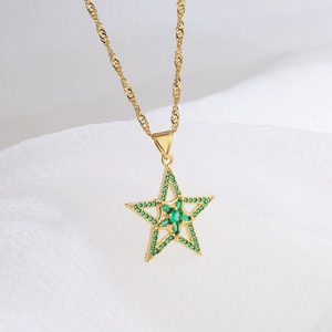 Gold plated star necklace with green zircons on white fabric background