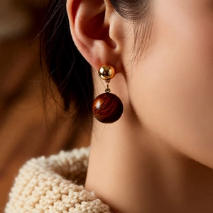 Macro view of 18k gold plated tiger eye stone ball drop earrings on model