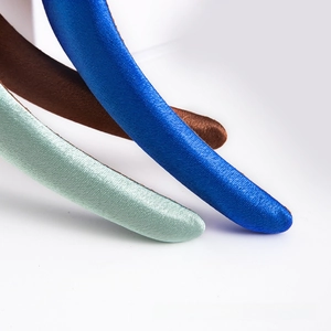 Macro detail of high-volume satin headbands in royal blue, brown, and mint green