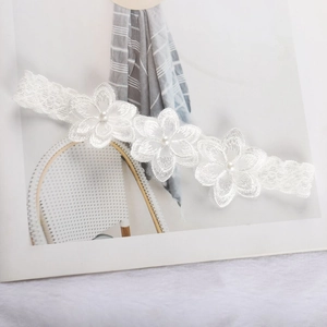 Detail of white lace hairband with chiffon flowers and pearls on white faux fur background