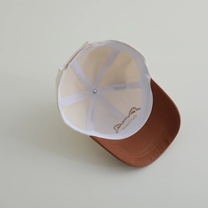 Détails de l'intérieur d'une casquette enfant beige avec coutures et broderie d'ours