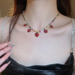 Close-up of golden necklace with colorful zircon accents and red heart-shaped pendants